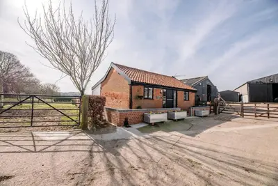 a brick house with a fence next to a field at The Old Dairy, Cookley in Cookley