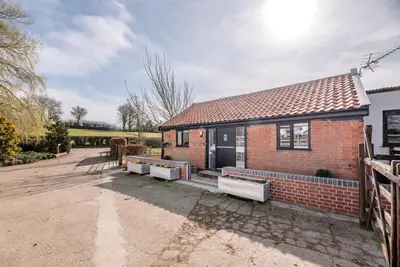 a red brick house with a fence in front of it at The Old Dairy, Cookley in Cookley