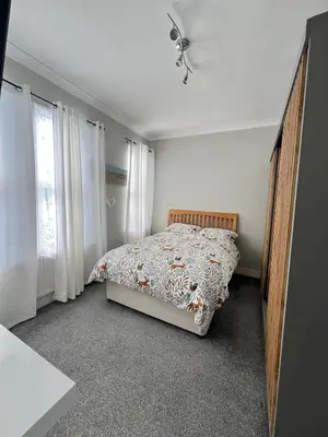 a bedroom with a bed in a room with windows at Dolce Vita on Sea in Southend-on-Sea