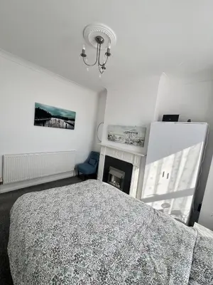 a white bedroom with a bed and a fireplace at Dolce Vita on Sea in Southend-on-Sea