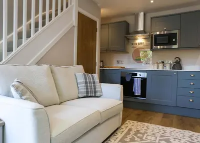 a living room with a couch and a kitchen at Gala Suite - The Apple Barn in Pettistree