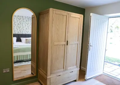 a bedroom with a wooden cabinet and a mirror at Russet Suite - The Apple Barn in Pettistree