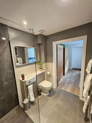a bathroom with a toilet and a glass shower at Russet Suite - The Apple Barn in Pettistree