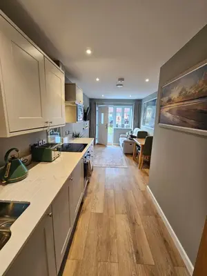 a kitchen with white cabinets and a wooden floor at Russet Suite - The Apple Barn in Pettistree