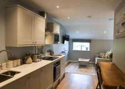 a kitchen with white cabinets and a wooden table at Discovery Suite - The Apple Barn in Pettistree