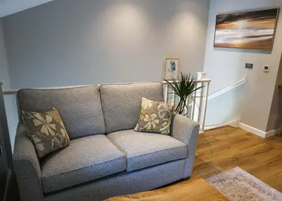 a gray couch in a living room with a painting at Discovery Suite - The Apple Barn in Pettistree