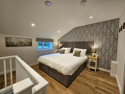 a bedroom with a large bed and a staircase at Cameo Suite - The Apple Barn in Pettistree