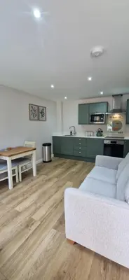a living room with a white couch and a kitchen at Cameo Suite - The Apple Barn in Pettistree