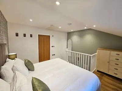 a bedroom with a large white bed and a staircase at Cameo Suite - The Apple Barn in Pettistree