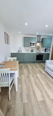 a kitchen with green cabinets and a wooden table at Cameo Suite - The Apple Barn in Pettistree