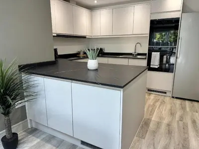 a kitchen with white cabinets and a black counter top at Abbey Rooms in Waltham Abbey