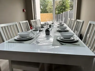 a white table with glasses and plates and chairs at Abbey Rooms in Waltham Abbey