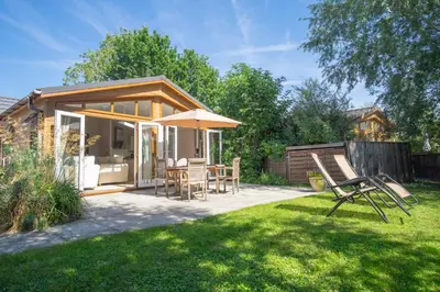 a patio with an umbrella and chairs in a yard at Welhams Meadow Holiday Lodges in Ringshall