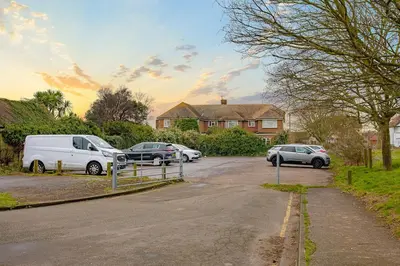 a parking lot with cars parked in front of a house at Coastal Charm In Clacton On Sea in Holland-on-Sea