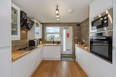 a kitchen with white cabinets and a stove top oven at Coastal Charm In Clacton On Sea in Holland-on-Sea