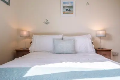 a bed with white pillows and two lamps at The Meadows Dairy, Bawdsey in Bawdsey