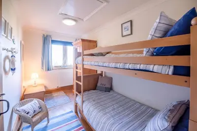 a room with two bunk beds and a chair at The Meadows Dairy, Bawdsey in Bawdsey