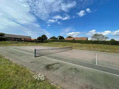 a tennis court with a net on top of it at The Meadows Dairy, Bawdsey in Bawdsey