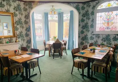a dining room with tables and chairs and stained glass windows at The Cobham Hotel in Southend-on-Sea