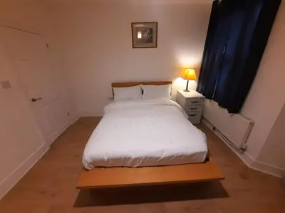 a bedroom with a white bed and a night stand with a lamp at Cozy Seaview Flat in Clacton-on-Sea