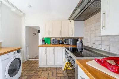 a kitchen with white cabinets and a washer and dryer at 5 Mill Cottage in Yoxford