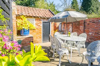 a table and chairs with an umbrella on a patio at 5 Mill Cottage in Yoxford