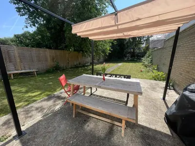 a wooden table and a chair under an umbrella at Luxury City House - 1 min from river - Parking - Sleeps 10 in Cambridge