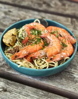 a blue bowl of shrimp and pasta on a wooden table at Black Horse in Brent Pelham