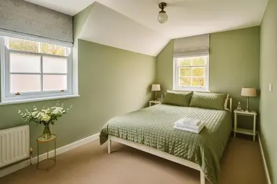 a green bedroom with a bed and two windows at Black Horse in Brent Pelham