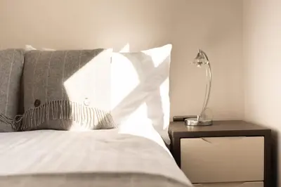 a bedroom with a bed with a lamp on a night stand at Vineyard Style 2BR with Garden and Parking in Shudy Camps