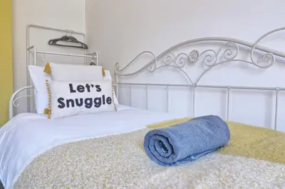 a white bed with a blue towel on it at Comfy 4 Bed, Sleeps 8, fast WIFI, Contractor friendly in Hythe