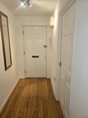 an empty hallway with a white door and wooden floors at Private Room in Hythe