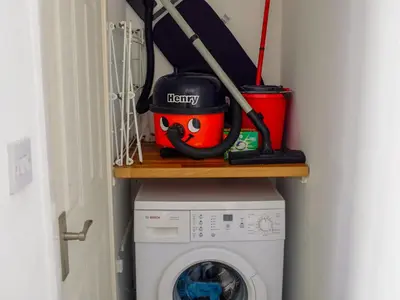 a laundry room with a washing machine and a mop at Cosy Cottage in Manningtree
