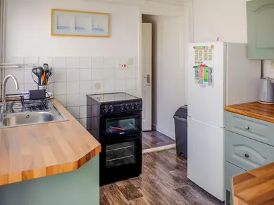a kitchen with a stove and a sink and a refrigerator at Cosy Cottage in Manningtree