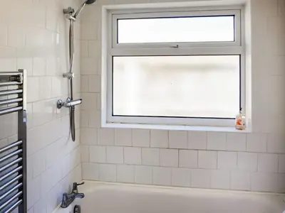 a bathroom with a window and a bath tub at Cosy Cottage in Manningtree