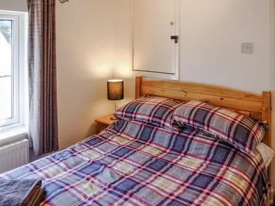 a bedroom with a bed with a plaid blanket at Cosy Cottage in Manningtree