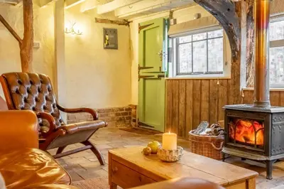 a living room with a fireplace and a chair at The Dairy at Green Valley Farm in Laxfield