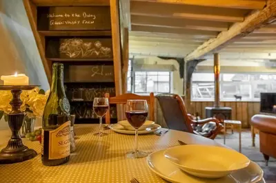 a table with two glasses of wine on it at The Dairy at Green Valley Farm in Laxfield