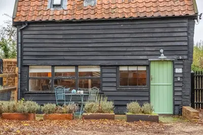 a black house with a green door and windows at The Dairy at Green Valley Farm in Laxfield