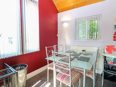 a dining room with red walls and a table and chairs at Rookyard Cottage in Halesworth