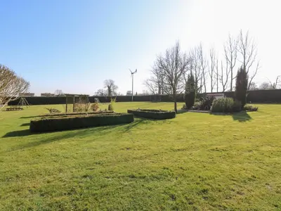 a field of grass with a windmill in the background at Rookyard Cottage in Halesworth
