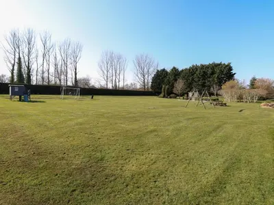 a large grass field with an empty field at Rookyard Cottage in Halesworth