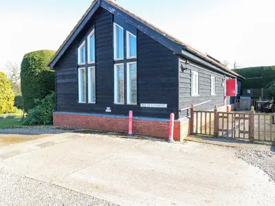 a black house with a wooden fence in front of it at Rookyard Cottage in Halesworth