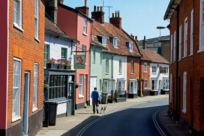 a man walking a dog down a street at Blossom House in Woodbridge