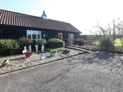 a house with a fence and some flowers in front of it at Swallow Barn in Halesworth