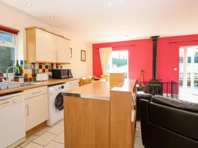 a kitchen with red walls and a kitchen with a stove at Swallow Barn in Halesworth