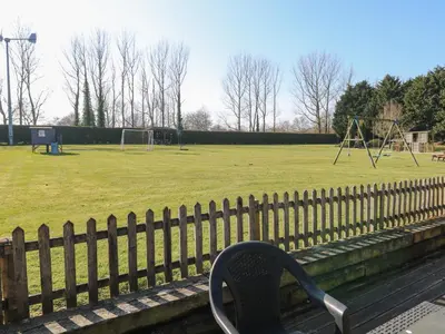 a park with a bench and a playground at Swallow Barn in Halesworth