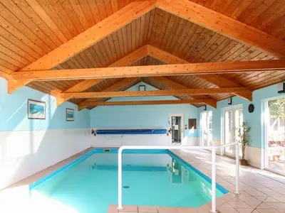 an indoor swimming pool with a wooden ceiling at Swallow Barn in Halesworth