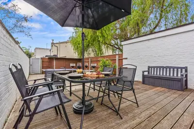 a table with chairs and an umbrella on a deck at Cozy accessible 2bd flat on Mill road with firepit for a lovely winters night in Cambridge
