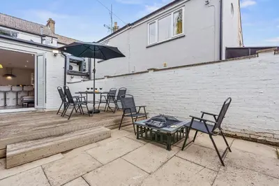 a patio with chairs and a table and an umbrella at Cozy accessible 2bd flat on Mill road with firepit for a lovely winters night in Cambridge